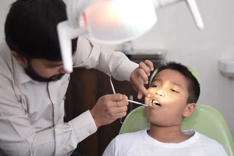 சிறுவனின் பற்களைப் பரிசோதிக்கும் பல் மருத்துவர்